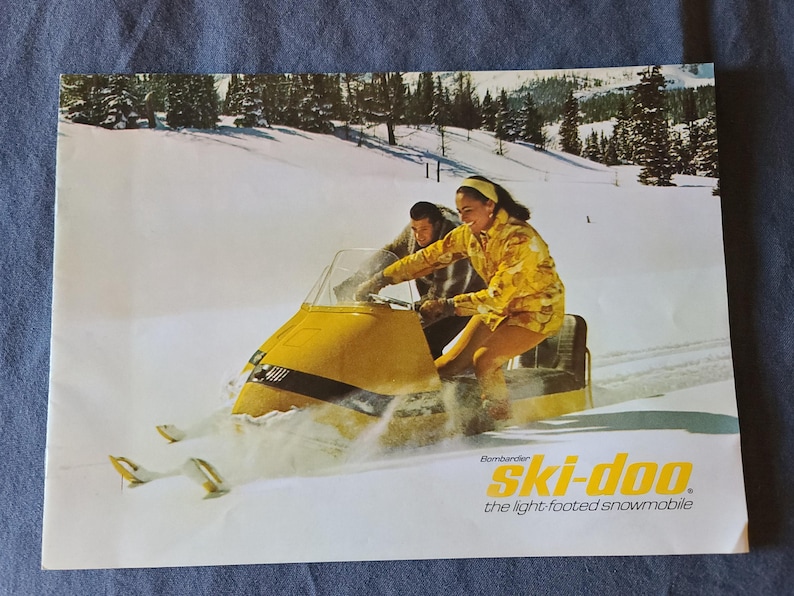 May include: A white ceramic mug with a black handle and the text "But First, Coffee" in a bold, black font. The mug is set against a blurred background, suggesting a cozy setting.