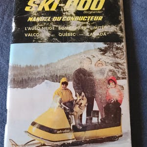 Puede incluir: Portada de manual de motos de nieve Ski-Doo vintage. La portada presenta una moto de nieve amarilla y negra con el texto "Ski-Doo" y "MANUEL DU CONDUCTEUR". Una familia y un perro est&aacute;n representados en un paisaje nevado. El manual es de Valcol, Quebec, Canad&aacute;.