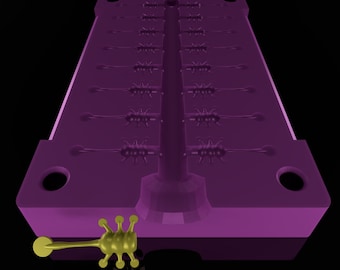 Puede incluir: Un molde de plástico morado con múltiples cavidades para fundir pequeños objetos con forma de estrella de punta. Un solo objeto con forma de estrella de punta de color dorado está acostado junto al molde.