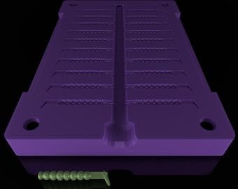 May include: A purple plastic mold with multiple cavities for making worm-shaped fishing lures. The mold has a central channel for pouring in the liquid plastic. A green worm-shaped lure is shown below the mold.