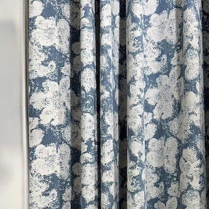 Może przedstawiać: Zbliżenie na niebieskie i białe wzorzyste zasłony. Tkanina ma fakturowany, abstrakcyjny wzór kwiatowy.