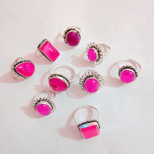 May include: Nine silver rings with pink gemstone settings. The rings have different styles of bands and settings. Some rings have a square setting, some have a round setting, and some have a more ornate setting.