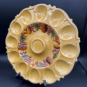 May include: A white ceramic mug with a black handle and the text "But First, Coffee" in a bold, black font. The mug is filled with a dark liquid, likely coffee, and sits on a light-colored surface.