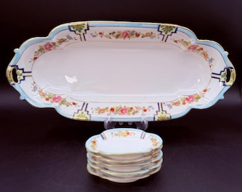 May include: A white porcelain serving tray with a light blue border, gold trim, and floral patterns, accompanied by a stack of five matching small round dishes. The tray features scalloped edges and integrated handles on both sides.