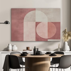 Könnte beinhalten: Abstrakte geometrische Wandkunst in Rosa-, Beige- und Weißtönen. Das Kunstwerk zeigt einen großen Bogen, Quadrate und einen Kreis. Die Kunst wird über einem Esstisch mit schwarzen Tellern und Stühlen ausgestellt.