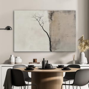 Könnte beinhalten: Abstrakte Leinwandkunst mit einer minimalistischen Baumsilhouette vor einem neutralen Hintergrund. Das Kunstwerk hat ein zweifarbiges Design mit Beige- und Brauntönen. Das Bild zeigt auch einen Esstisch mit schwarzen Stühlen, Tellern und dekorativen Gegenständen.