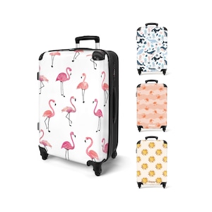 May include: A white suitcase featuring a pattern of pink flamingos. The suitcase has a black handle and frame, with four black wheels. Other suitcases with various patterns are also displayed.
