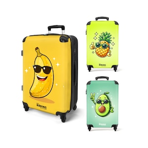 May include: Three rolling suitcases with fruit-themed designs. The largest suitcase is yellow with a smiling banana wearing sunglasses. The other two are green, one with a pineapple and the other with an avocado, both wearing sunglasses. All have black handles and wheels.