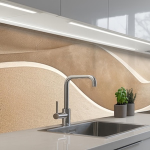 Può includere: Un lavello da cucina moderno con un rubinetto cromato. Il paraschizzi presenta un design testurizzato a forma di onda nei toni del beige e del crema. Due piccole piante in vaso sono sul piano di lavoro. Sopra, ci sono due lunghe e luminose luci a LED.