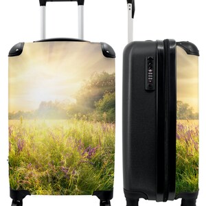 Koffer - handbagage - bloemen - gras - landschap - zon - bomen