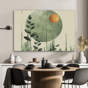 Può includere: Arte astratta su tela con un cerchio verde acquerello con un sole arancione. Sagome di piante verde scuro e pennellate su sfondo beige. L'opera d'arte è esposta sopra un tavolo da pranzo con sedie e stoviglie nere.