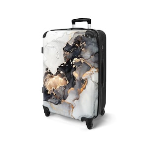 May include: A rolling suitcase with a black frame and handle. The suitcase features a white, black, and gold abstract design on the front. The design resembles marble or ink art. The suitcase has four black wheels.
