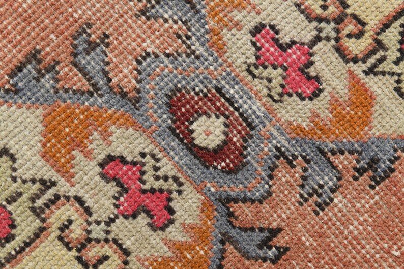 May include: Close-up of a woven rug with a detailed pattern in shades of red, orange, blue, and beige.
