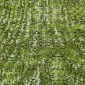 May include: Green vintage rug with a faded floral pattern. The rug has a distressed look and a subtle sheen.
