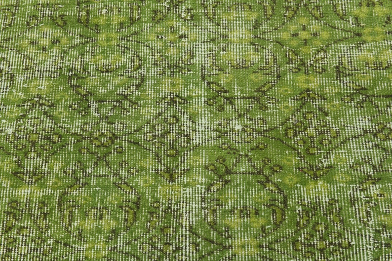 May include: Green vintage rug with a faded floral pattern. The rug has a distressed look and a subtle sheen.