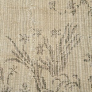 May include: Beige and gray floral patterned rug. The rug features a detailed design of flowers and leaves in shades of gray against a beige background. The rug has a vintage, distressed appearance.