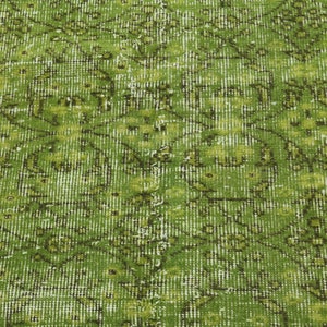 May include: A green vintage rug with a faded floral pattern. The rug has a distressed look and is made of a woven material.
