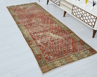 Puede incluir: Una alfombra de pasillo vintage con un patrón geométrico con una forma de diamante en el centro. Los colores son rojo, beige y crema.