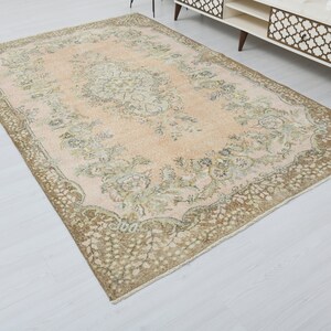 May include: A vintage rug with a light pink background and a brown floral pattern. The rug has a distressed look and is perfect for adding a touch of bohemian style to your home.