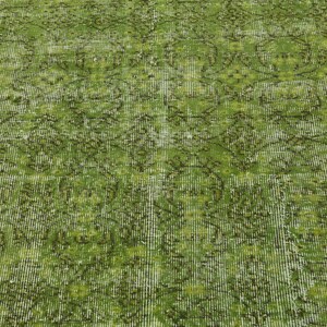 May include: A green vintage rug with a faded floral pattern. The rug has a distressed look and a textured surface.