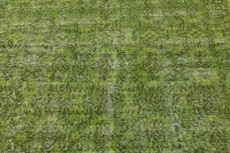 May include: A green vintage rug with a faded floral pattern. The rug has a distressed look and a textured surface.
