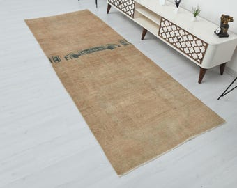 Puede incluir: Una alfombra de pasillo rectangular de color beige con un aspecto descolorido. La alfombra tiene un diseño de borde azul oscuro cerca del centro. La alfombra está colocada sobre un suelo de madera clara.
