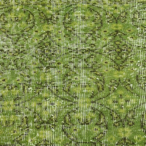 May include: A green vintage rug with a floral pattern. The rug has a distressed look and is made of a soft, woven material.