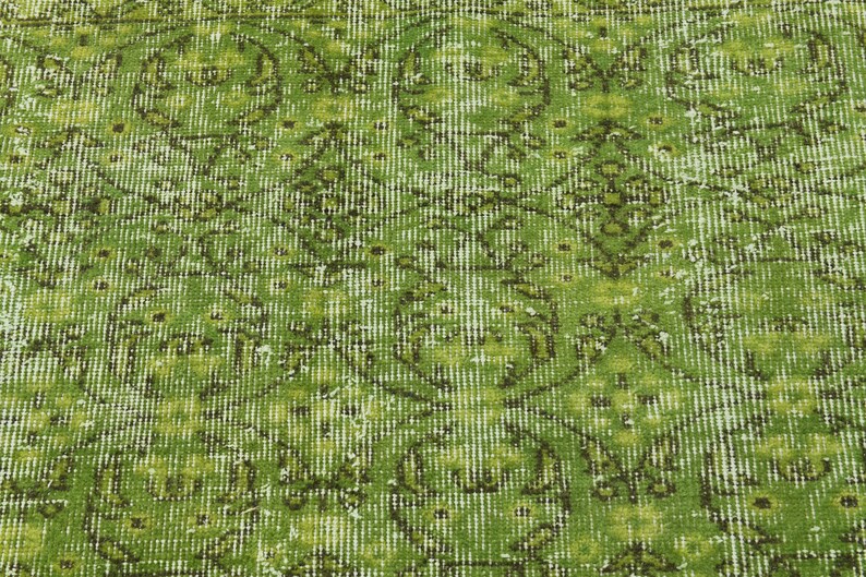 May include: A green vintage rug with a floral pattern. The rug has a distressed look and is made of a soft, woven material.