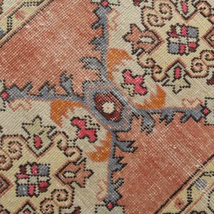 May include: Close-up of a vintage rug with a detailed geometric pattern in shades of red, orange, blue, and beige.
