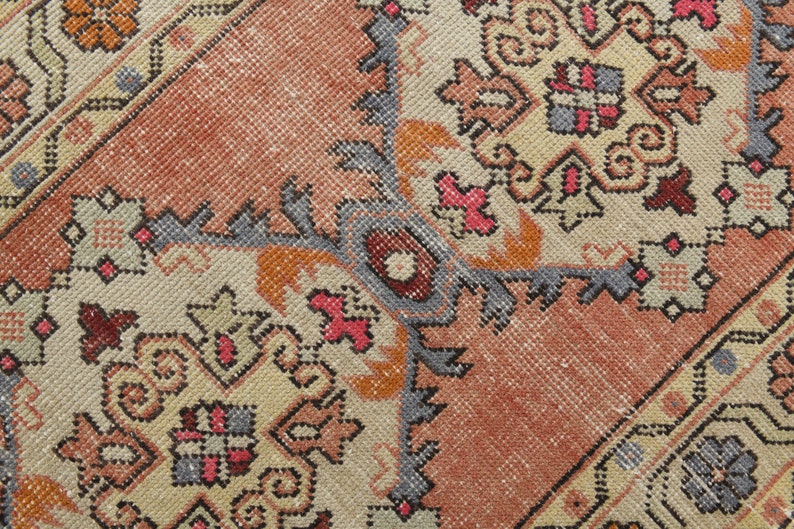 May include: Close-up of a vintage rug with a detailed geometric pattern in shades of red, orange, blue, and beige.