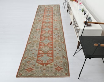 May include: A long, rectangular runner rug with a traditional Persian design. The rug has a red background with intricate patterns in shades of beige, cream, and blue.