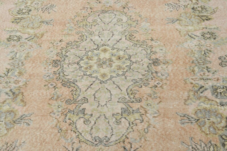 May include: A vintage rug with a faded floral pattern in shades of beige, brown, and blue. The rug has a distressed look and a worn texture.