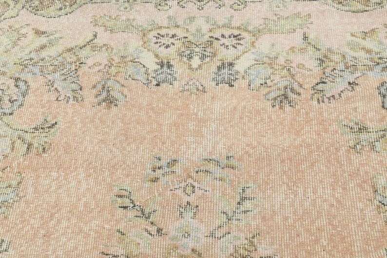 May include: A vintage rug with a floral pattern in shades of pink, beige, and brown. The rug has a distressed look and is woven with a fine texture.