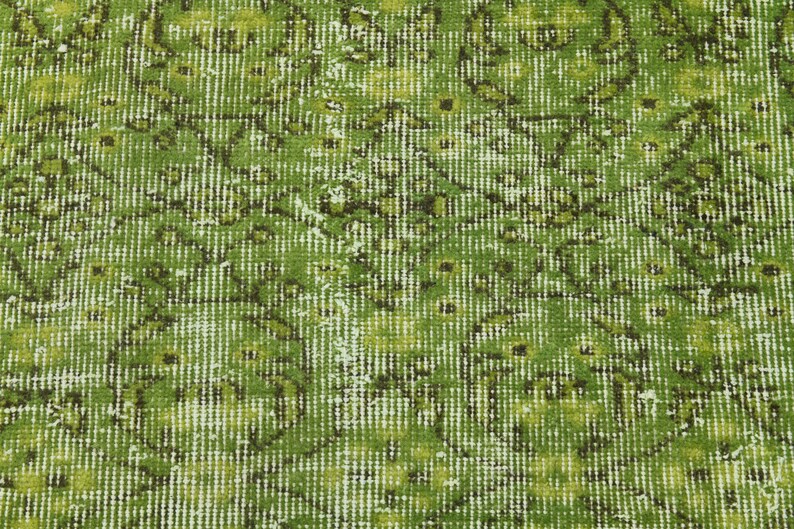 May include: A green rug with a faded floral pattern. The rug has a distressed look and is made of a soft, woven material.