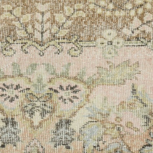 May include: Close-up of a pink and brown patterned rug with a floral design. The rug has a woven texture and is made of wool.