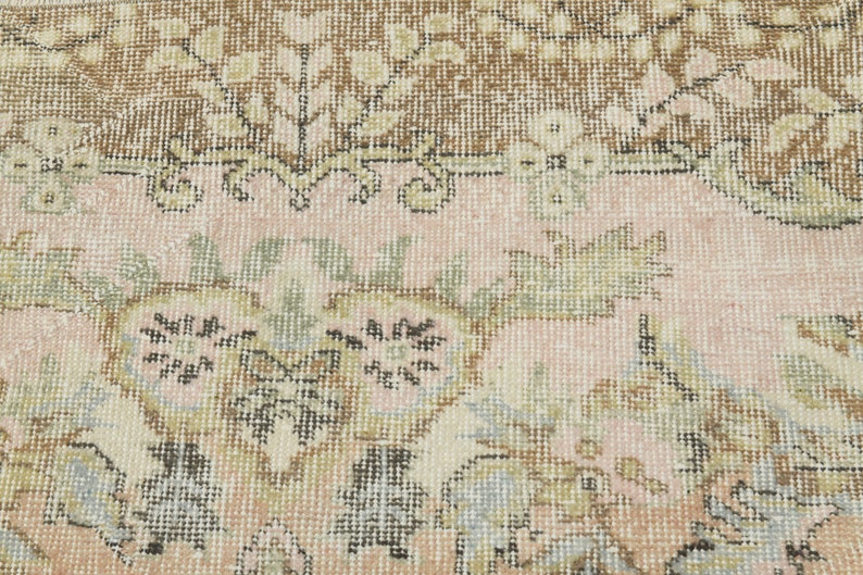 May include: Close-up of a pink and brown patterned rug with a floral design. The rug has a woven texture and is made of wool.