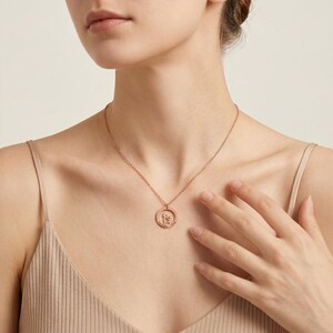 May include: A rose gold-toned necklace featuring a delicate chain and a circular pendant. The pendant contains a cutout silhouette of a person holding a small dog, with the text "THE BEST FRIEND" engraved along the bottom edge of the circle.