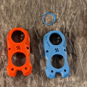 May include: Two 3D printed plastic cases, one orange and one blue, with a circular design and two holes.