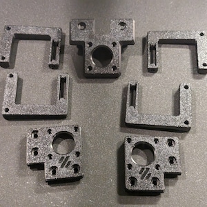 May include: A set of six black plastic 3D printed parts for a 3D printer. The parts are designed to be used as brackets or mounts.