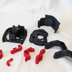 May include: A set of 3D printed parts for a project. The parts are black and red. There are six red parts and four black parts.
