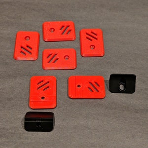 May include: Eight red plastic pieces with a geometric pattern and a small hole in the center. Two black plastic pieces with a hole in the center.