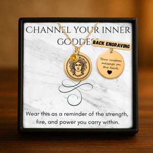 Könnte beinhalten: Goldfarbene Halskette mit zwei Anhängern, einer rund mit einem Medusa-Design und einem gelben Edelstein, der andere ein leerer Kreis. Der Text "CHANNEL YOUR INNER GODDESS" steht oben, mit "BACK ENGRAVING" und "Your custom message on the back".