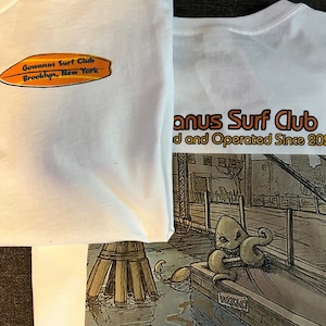May include: White t-shirt with a graphic print of a cartoon octopus and the text "Gowanus Surf Club" and "Waiting for the Perfect Wave" Brooklyn, New York.