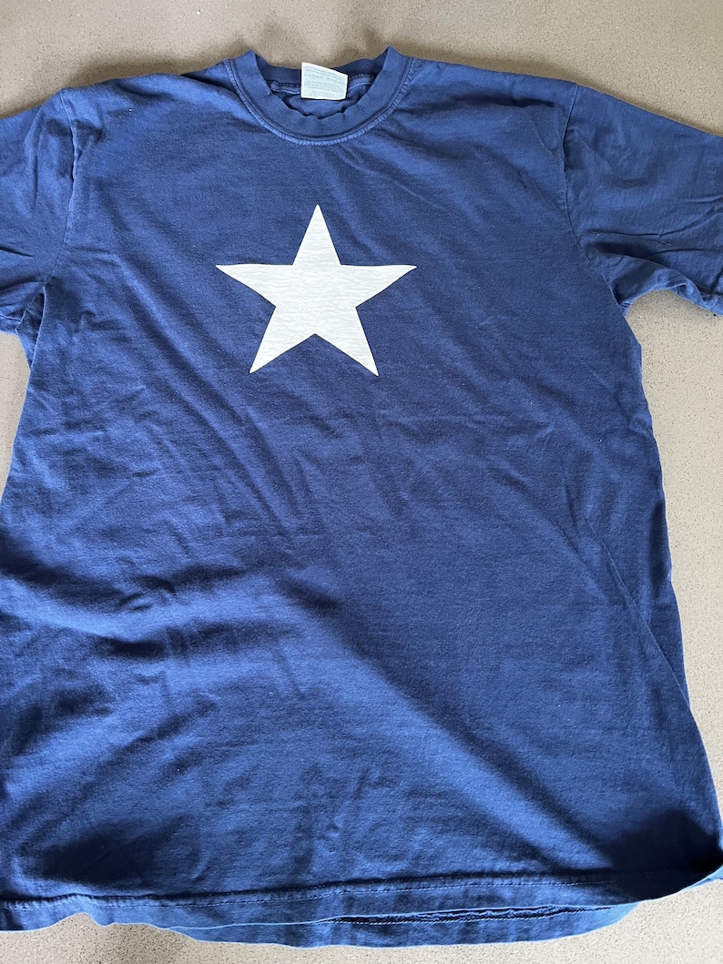 May include: A navy blue t-shirt with a large white star printed on the front.