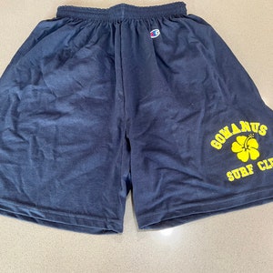 May include: Navy blue Champion athletic shorts with a yellow logo that says "Gomarus Surf Club" and a yellow hibiscus flower.