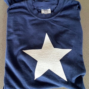May include: A navy blue t-shirt with a white star printed on the front. The shirt has a tag that says "Comfort Colors".