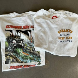 以下が含まれることがあります： モンスターのグラフィックプリントと「GOWANUS SURF CLUB Brooklyn, New York」の文字がプリントされた白いTシャツ2枚。もう一枚のTシャツには「GOWANUS Brooklyn NYC SURF CLUB」の文字がプリントされています。