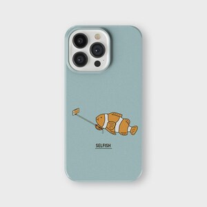 Op de afbeelding: Een lichtblauwe telefoonhoes met een cartoonillustratie van een oranje en witte vis die een selfie maakt met een selfie-stick. De tekst "SELFISH" staat onder de vis.