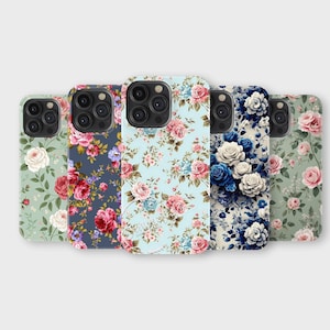 以下が含まれることがあります： 花柄の携帯電話ケースのコレクション。ケースには、ピンク、青、白の色合いのバラやその他の花のデザインが施され、緑、青、ネイビーの背景に配置されています。