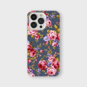 以下が含まれることがあります： 花柄のスマートフォンケース。ケースは、ピンク、赤、紫のバラと緑の葉の繰り返し模様のダークブルーの背景が特徴です。ケースは光沢のある仕上がりです。
